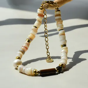 Gros plan détaillé du bracelet en coquillage naturel et perle avec pierre d'œil de tigre.