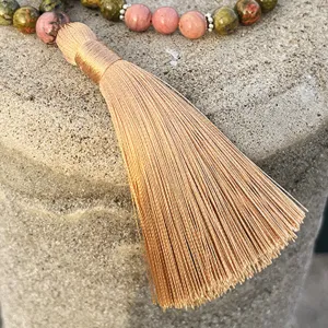 Detailed close-up view of natural stone beaded necklace with a golden tassel ornament.