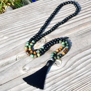 Primo piano di una collana di perline boho con nappa nera e bellissime pietre preziose naturali.