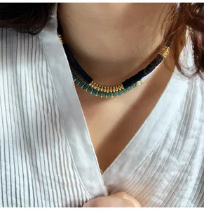 Close up detail of layered polymer clay beaded necklace with gold metal spacer rings.