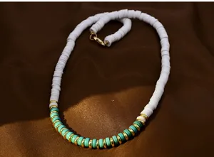 Detail shot of a stylish white and turquoise clay bead short necklace with gold-tone spacers.