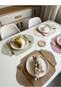 Elegant leather placemat set with irregular oval design for chic dining table decor.