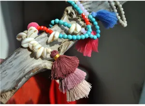 Handmade bohemian style beaded necklace detail featuring turquoise beads, shells, and colorful tassels.