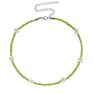 Collana di perline verdi con ciondoli a margherita bianca e catenella di estensione in argento.