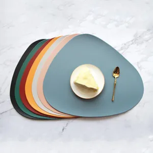 Detail view of colorful irregular placemats set with plate and spoon on marble table.