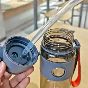 Detailansicht der Sportflasche mit Trinkhalm, Silikonhülle sowie tragbarem rotem Riemen.