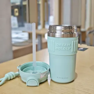 Detail shot of stainless steel coffee cup with silicone sleeve and portable straw lid.
