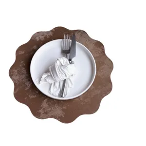 Geschulpte kunstlederen placemat met wit keramisch bord en bestekset voor elegante tafeldekking.