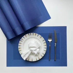 Detailed view of blue woven PVC placemat set with elegant plate and cutlery setup.