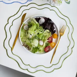 Scalloped embroidered table placemat, white fabric with green border for dining table decor.