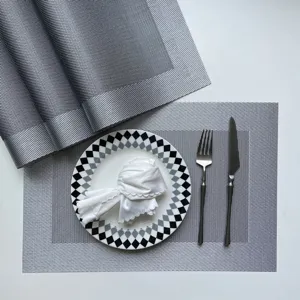 Detail shot of grey woven PVC placemat with elegant black and white checkered plate and cutlery set.