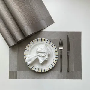 Detail shot of grey woven PVC placemat featuring heat insulation and non-slip design for dining tables.