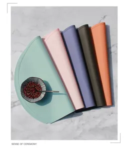 Vue détaillée de sets de table en silicone couleur Morandi roulés sur table en marbre.