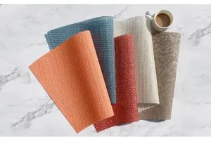 Vista dettagliata di tovagliette in PVC curve multicolore su piano in marmo con tazza caffè.
