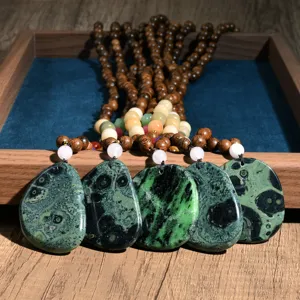 Close-up details of the vintage wooden bead and green patterned stone pendant long necklace.