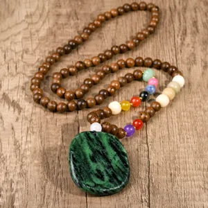 Close-up detail of vintage wooden beaded necklace with natural green stone pendant.