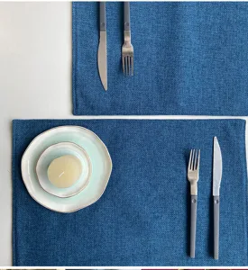 Detailed top view of blue faux linen placemat paired with tableware and candle decor