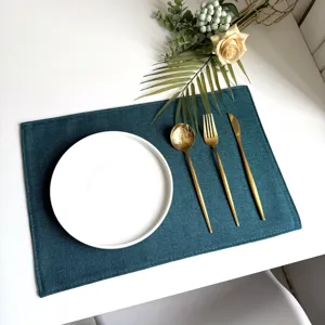 Detailed view of dark green linen textured placemat with white plate and gold cutlery setup.