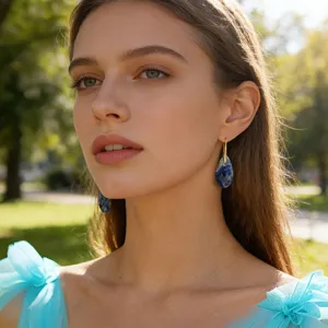 Close-up detail of elegant blue teardrop stone earrings worn by a model in soft outdoor light.