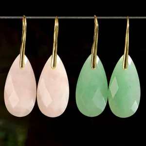 Close-up detail shot of elegant multi-faceted teardrop gemstone earrings with gold hooks.