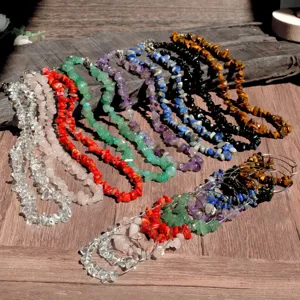 Detail view of colorful chip stone necklaces and matching hoop earrings set on wooden surface.