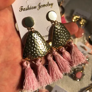 Boucles d'oreilles pendantes géométriques texturées dorées avec de longs glands roses.