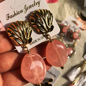 Boucles d'oreilles coquillage dorées avec pendentifs ovales en résine rose style bohème.