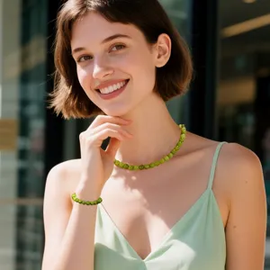 Primer plano de un conjunto de joyas de collar y pulsera de cuentas verdes llevado por modelo.