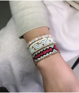 Primer plano detallado de un conjunto de pulseras bohemias multicapa con cuentas y tejido.