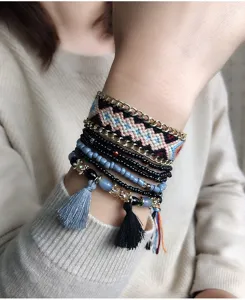 Pulsera bohemia multicapa con tejido étnico, cadenas de metal, cuentas y borlas encantadoras.