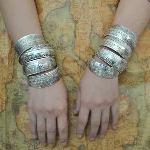 Bracciali rigidi etnici vintage impilati in argento con motivi floreali e animali dettagliati.