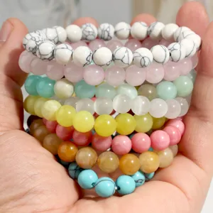 Detailed closeup of colorful natural stone beaded bracelets stacked in hand, vibrant gemstone styles.