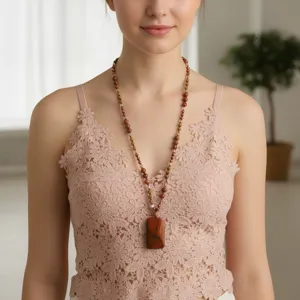 Dettaglio di una lunga collana di perle in pietra naturale con ciondolo rettangolare elegante.
