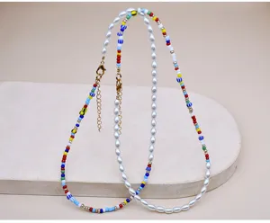 Dettaglio collana a sovrapposizione con perline colorate e perle ovali e chiusura in metallo.