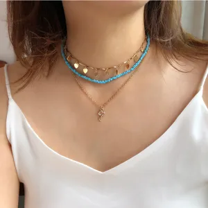 Set di collane girocollo multistrato boho con perline blu, cuori dorati e ciondolo.