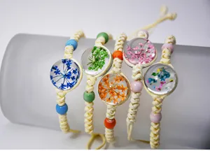 Bracciale intrecciato a mano in cotone di canapa con fiori secchi colorati in cabochon di vetro.