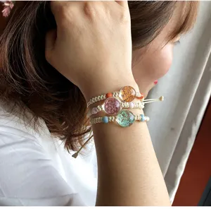 Dettaglio bracciale in canapa intrecciata a mano, ciondolo fiore secco resina, stile boho.