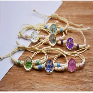 Bracciale intrecciato in canapa e cotone fatto a mano con fiori secchi colorati, dettaglio boho.