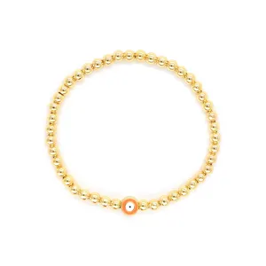Vue détaillée d'une breloque œil porte-bonheur orange sur un bracelet en perles d'or 18K.
