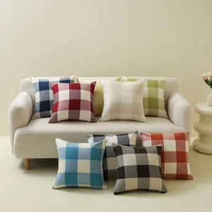 Verschiedene karierte Kissenbezüge auf einem minimalistischen cremefarbenen Sofa präsentiert