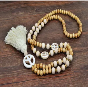 Détail en gros plan du collier de perles en bois bohème avec pompon et pendentif signe de paix.
