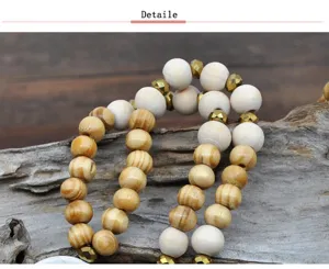 Vue détaillée du long collier en perles de bois blanches et naturelles avec intercalaires dorés.