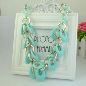 Closeup view of a chunky mint green and gold chain statement necklace hanging on a photo frame.