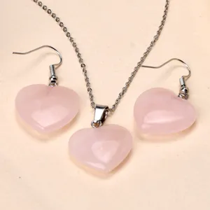 Close-up detail of natural pink crystal heart pendant necklace and matching earrings jewelry set.