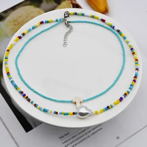 Primo piano di collana di perline a doppio strato con perline colorate, croce bianca e ciondolo.