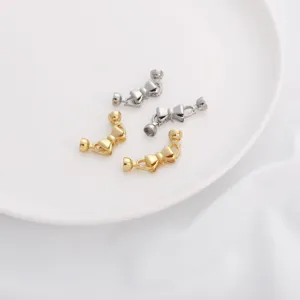 Close-up view of metal bow necklace connectors, glossy gold and silver DIY jewelry findings.