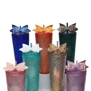 Detailed shot of glitter bow studded tumbler cups with straw, colorful aesthetic drinkware.