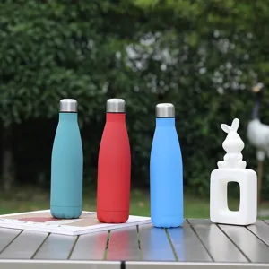 Stainless steel vacuum cola water bottle detail shot featuring colorful insulated mugs outdoors.