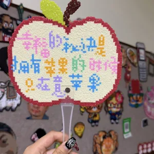 Handgemaakte strijkkralen appel waaier detail weergave, DIY ambacht accessoire pixel art.