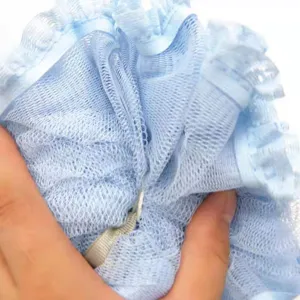 Detailweergave van blauwe netbadpons, dubbellaagse douchepuf met kantrand en ophangkoord.